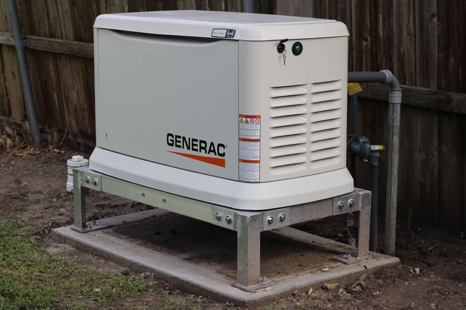 A Generac standby generator set on a galvanised steel platform above its concrete pad, with the gas regulator and piping run in alongside