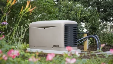 A certified technician installing a KOHLER standby generator outside a modern U.S. home, representing nationwide service coverage.